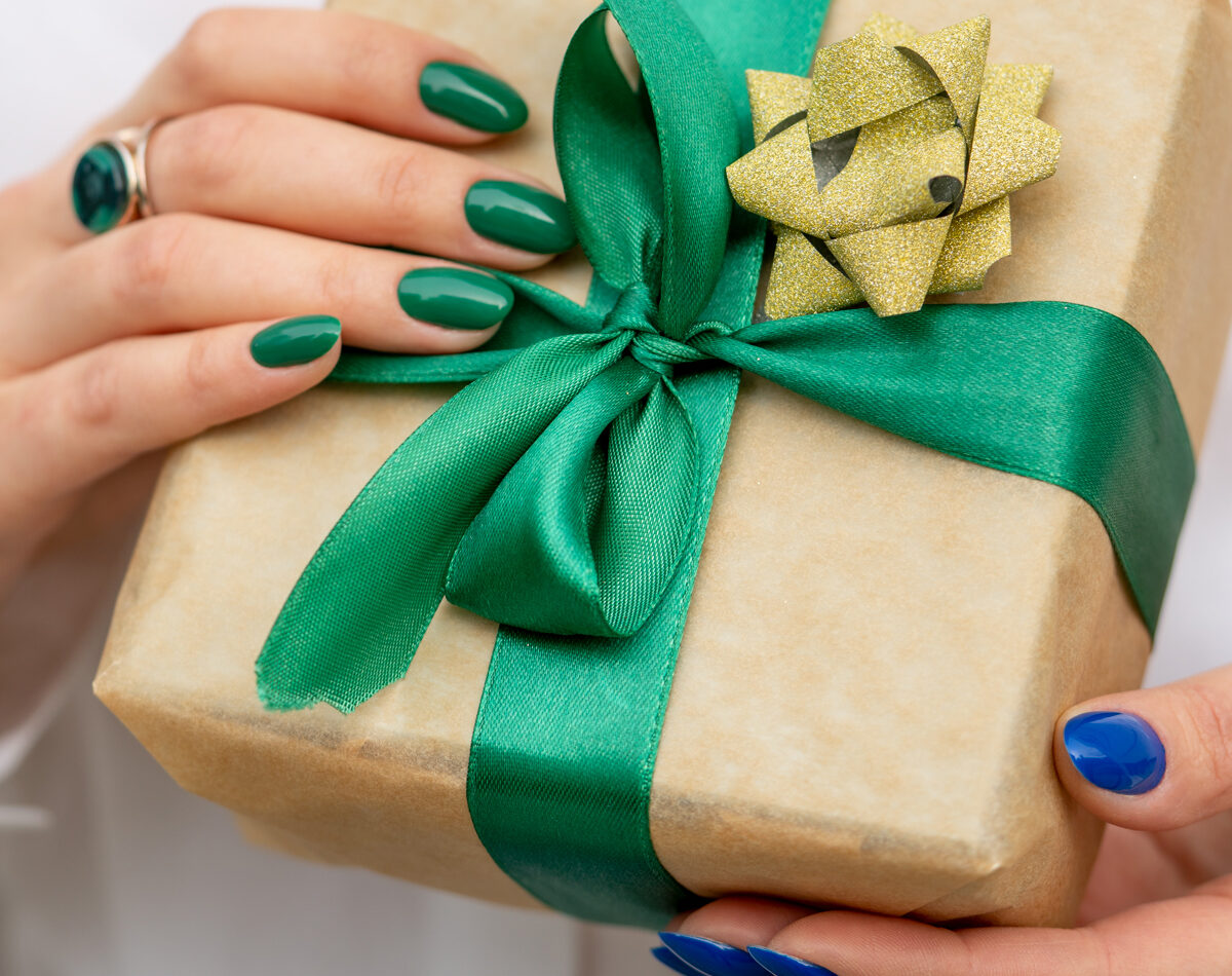 hånd med pen manikyr som overrekker julegave